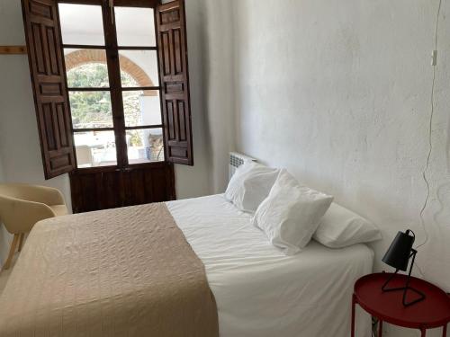 Schlafzimmer mit einem Bett mit weißer Bettwäsche und einem Fenster in der Unterkunft Apartamentos El Cabo in Mairena