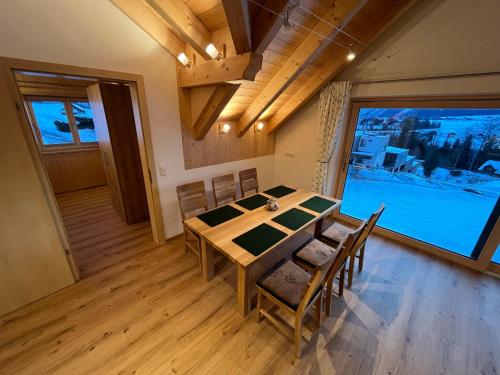 ein Esszimmer mit einem Tisch und Stühlen sowie einem großen Fenster in der Unterkunft Ferienwohnungen Kalss nahe Altaussee in Bad Aussee