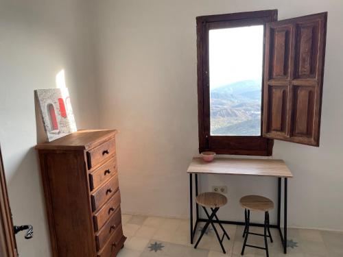 a bedroom with a dresser and a window and two stools at Apartamentos El Cabo in Mairena