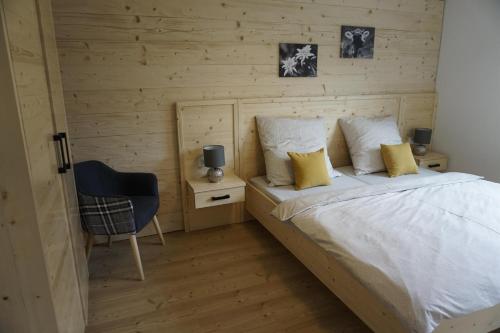 a bedroom with a white bed and a chair at Ferienwohnung Helchenberg in Bad Hindelang