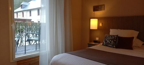 a bedroom with a bed and a window with a balcony at Mercure Dinan Port Le Jerzual in Dinan