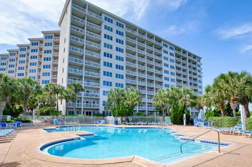 a large apartment building with a swimming pool and palm trees at TOPS'L Summit 706 A in Destin