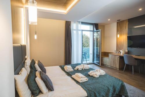a bedroom with a large bed with towels on it at Hotel Zena Beauty & Shopping Center in Hévíz