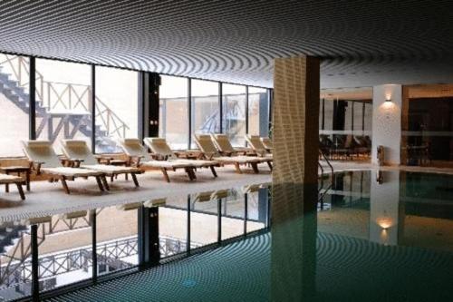 班斯科Dinos 2 Bed Cozy Apart at Bansko close to the lift的建筑物内的游泳池，配有椅子和游泳池