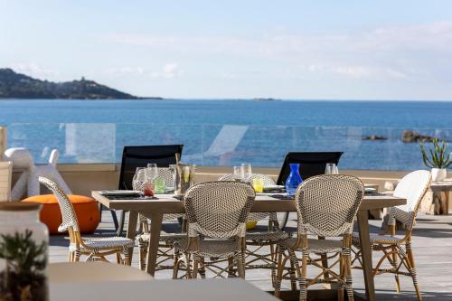 una mesa y sillas en un patio con vistas al océano en La Maison sur la Plage, en Calcatoggio