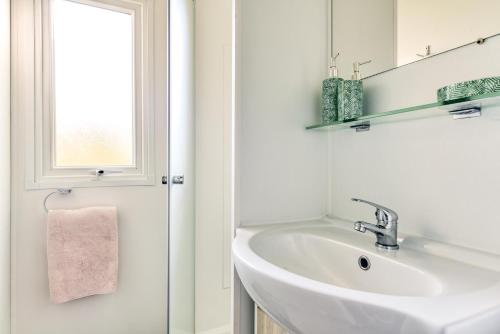 a white bathroom with a sink and a window at Camping maeva Club Argelès Vacances in Argelès-sur-Mer