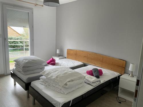 a bedroom with two beds with white sheets and pink pillows at Villa MARIA in Chambon-sur-Lac