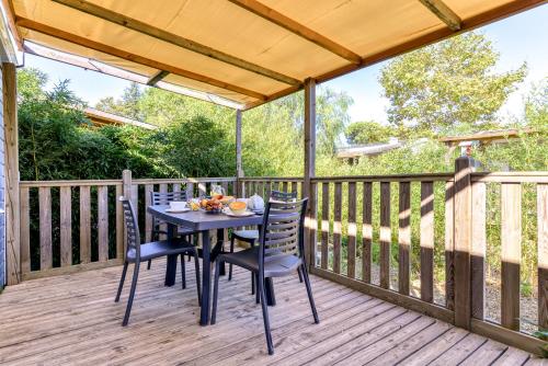 a wooden deck with a table and chairs on it at Camping maeva Club Argelès Vacances in Argelès-sur-Mer