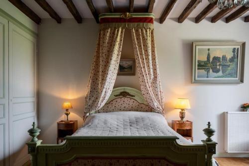 a bedroom with a canopy bed and two lamps at Un Logis en Angoumois in Rancogne