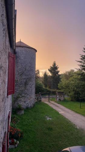 a stone wall next to a road with a fence at Un Logis en Angoumois in Rancogne