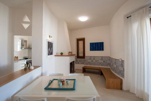 Il comprend un salon avec une table blanche et une cuisine. dans l'établissement Villa Pineta, à Valledoria