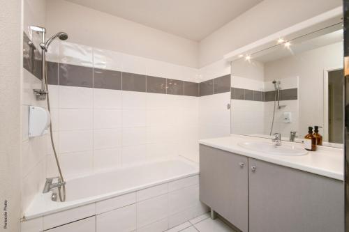 une salle de bain blanche avec une baignoire et un lavabo dans l'établissement NOCNOC - Le Cocon Hypercentre, à Toulouse