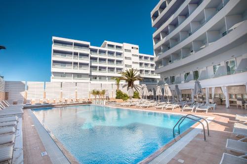 a swimming pool with lounge chairs and a large building at Rhodos Horizon Blu-Adults Only in Rhodes Town