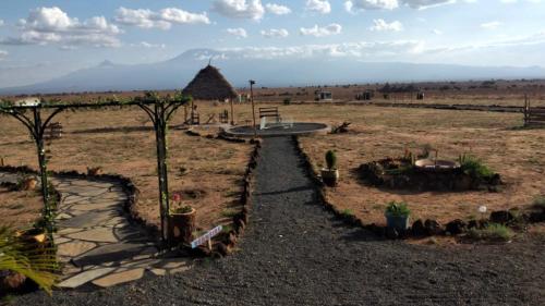 Amanya Double Pitch Tent with Mt Kilimanjaro View في أمبوسيلي: طريق في ميدان فيه اشجار ومبنى