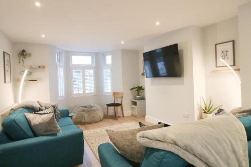 a living room with a blue couch and a tv at Townhouse, close to harbour with sea views in Padstow