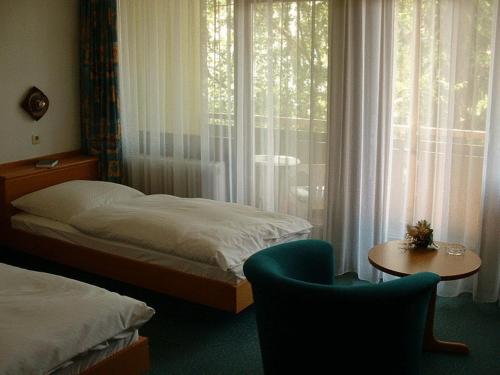 Schlafzimmer mit einem Bett, einem Tisch und einem Fenster in der Unterkunft Hotel Koch Maingau in Obertshausen