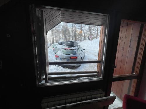 een uitzicht op een auto geparkeerd in de sneeuw door een raam bij Cervinia appartamento monolocale in Breuil-Cervinia
