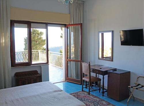 sypialnia z łóżkiem i biurkiem oraz balkon w obiekcie Hotel Mediterranée w Taominie