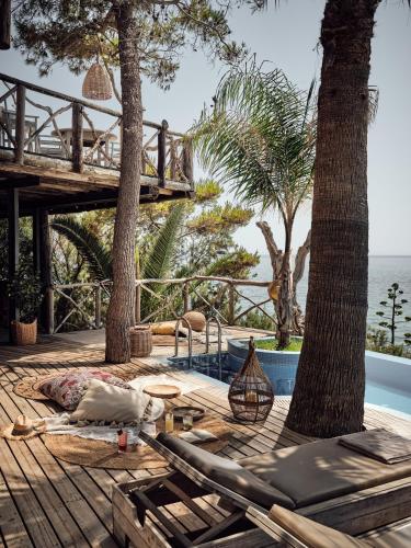 a deck with chaise lounge chairs and a swimming pool at Gloria Maris Hotel Suites and Villas in Laganas