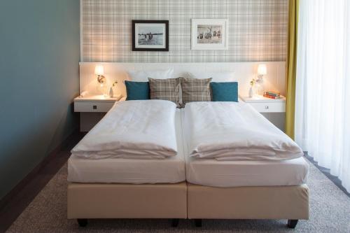 a bedroom with a large bed and a sink at Dorint Resort Baltic Hills Usedom in Korswandt