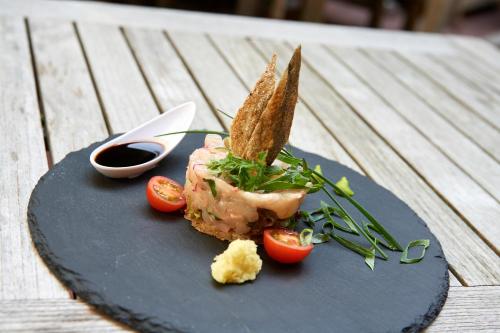 a plate of food with meat and tomatoes on a table at Hotel & Restaurant Linde in Münstertal