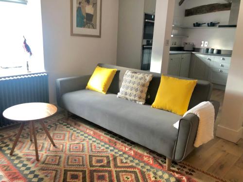 un sofá gris con almohadas amarillas en la sala de estar en 3 The Olde Barn Apartments en Stamford