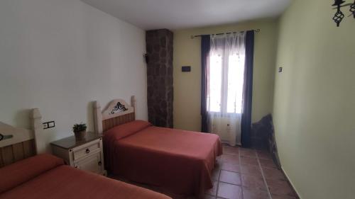 a bedroom with two beds and a window at Alojamientos Rurales Los Molinos in Fuentes de León