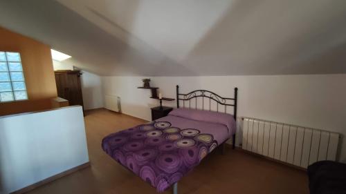 a bedroom with a bed with a purple comforter at Alojamientos Rurales Los Molinos in Fuentes de León