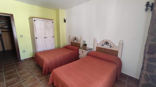 a hotel room with two beds and a door at Alojamientos Rurales Los Molinos in Fuentes de León