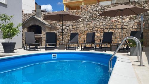 a swimming pool with chairs and umbrellas next to a building at Apartment Delic in Crikvenica