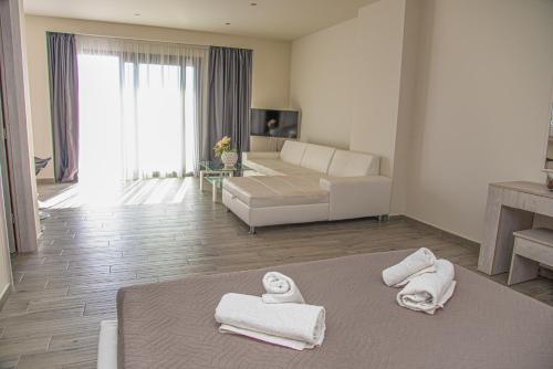 a living room with a couch and towels on a bed at Tereza's Sunset Hotel in Agios Stefanos