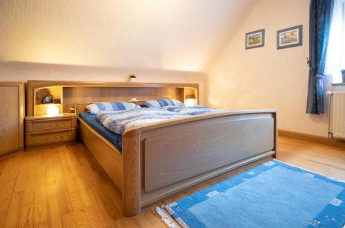 a bedroom with a wooden bed with a blue rug at Ferienhaus Schaumbergblick in Britten