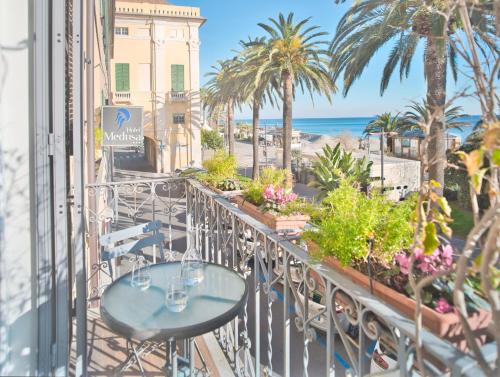 a balcony with tables and palm trees and the ocean at Medusa Apartment - Dépendance in Finale Ligure
