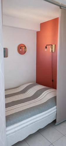Ce lit se trouve dans une chambre dotée d'un mur rouge. dans l'établissement 65 Rue Pierre Rameil Appartement, à Cavalaire-sur-Mer