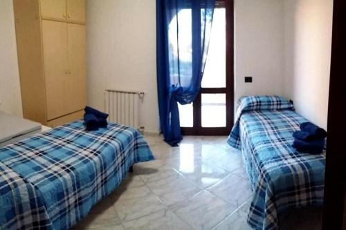 a bedroom with two beds with blue sheets and a window at Appartamento La Rocca in Tortolì