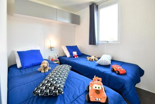 a room with blue beds with stuffed animals on them at Camping maeva Club Argelès Vacances in Argelès-sur-Mer