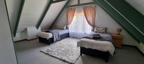a attic room with two beds and a window at DullVino Cottage @ Critchley in Dullstroom