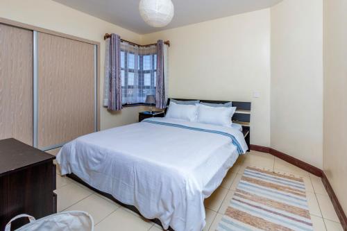 1 dormitorio con cama blanca y ventana en Westpoint Suites by Senga en Nairobi