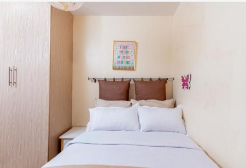 a bedroom with a bed with white sheets and pillows at Westpoint Suites by Senga in Nairobi