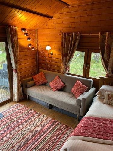 a living room with a couch in a log cabin at Heart of Glencoe Holidays in Glencoe