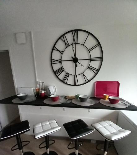 a large clock on the wall above a table with chairs at Hyper centre, appart F2 refait à neuf (TV+++) in Vire