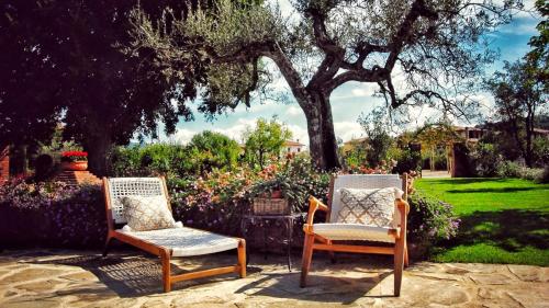 two chairs and a table in a garden at CASALE BELLA VITA 8&4, Emma Villas in Città della Pieve