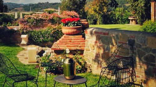 a garden with a table and chairs and a brick wall at CASALE BELLA VITA 8&4, Emma Villas in Città della Pieve