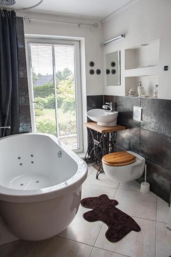 a bathroom with a tub and a toilet and a sink at Allika Holiday House in Pärnu