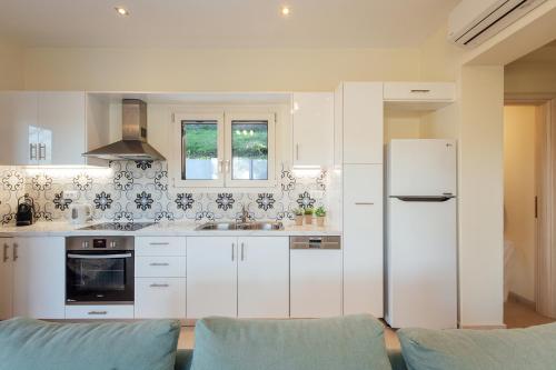 a kitchen with white cabinets and a refrigerator at Villa Breeze & Villa Coco by Konnect, Avlaki Beach in Kassiopi