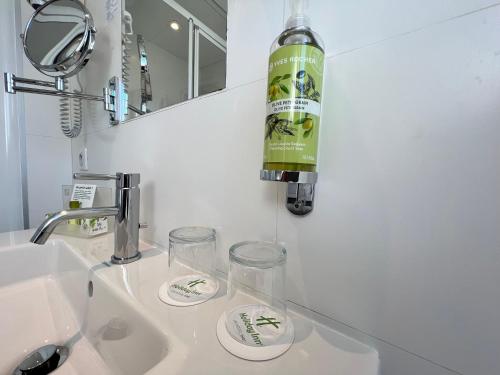 a bathroom with two sinks and a bottle on the wall at Holiday Inn Paris-Auteuil by IHG in Paris