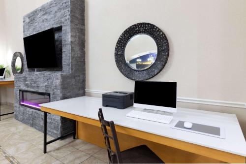 a desk with a computer on it with a fireplace at La Quinta by Wyndham Garland Harbor Point in Garland