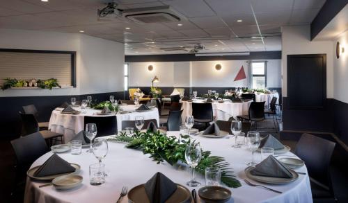 a dining room with tables with white tablecloths and flowers at Atura Wellington in Wellington