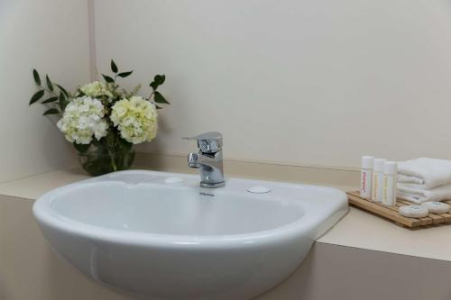 a white sink in a bathroom with a vase of flowers at Atura Wellington in Wellington