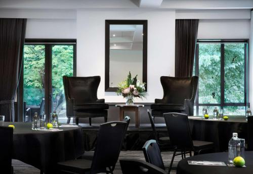 a dining room with tables and chairs and windows at Rydges Latimer Christchurch in Christchurch